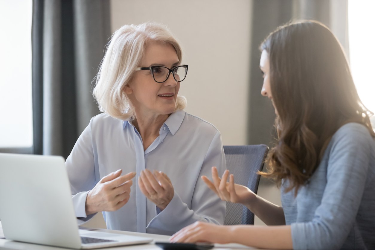 Different-ages-employees-sitting-at-desk-working-together-discussing-project-1147384767_1258x838